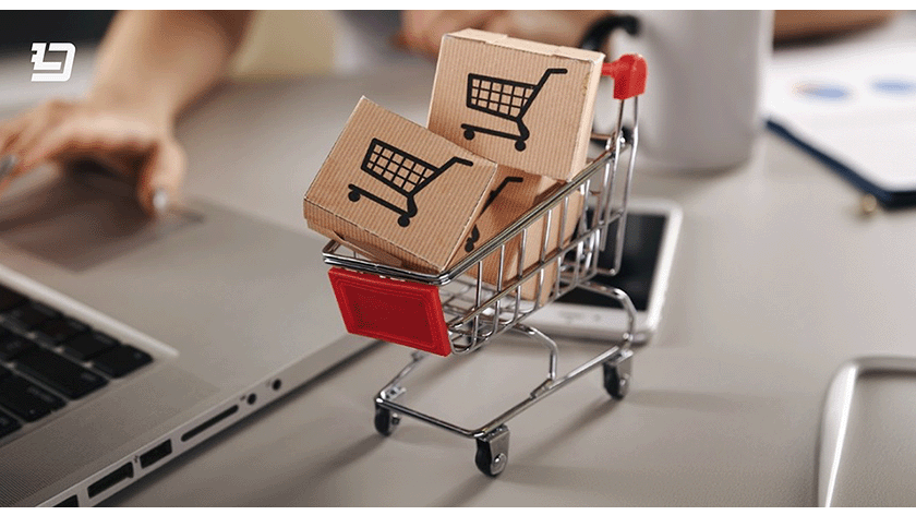 Small shopping cart with product boxes placed near a laptop, representing emerging eCommerce trends for 2024